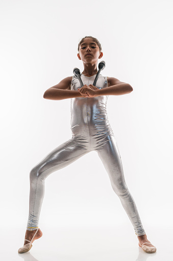 Beautiful gymnast  juggling teenage girl doing exercise with stick in studio on white background