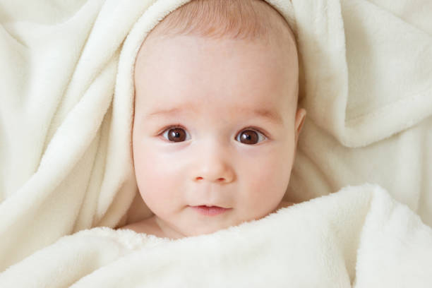 istock cute baby lying in bed covered with soft blanket 1042606930