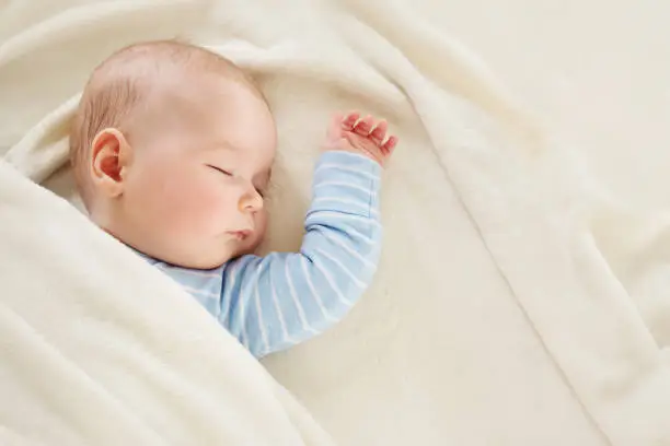 Photo of Baby sleeping covered with soft white blanket