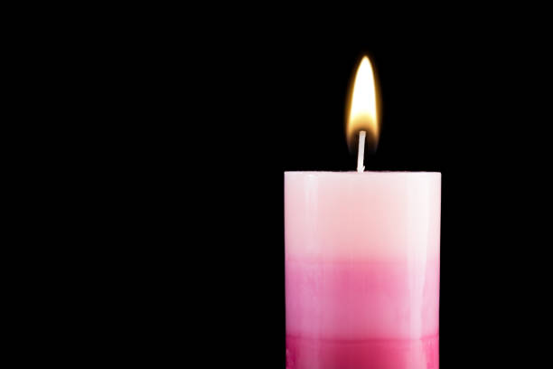 Beautiful purple decorative wax candle burning isolated on black background. Empty space for text. Close up, selective focus
