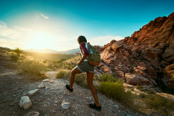 woman hiking at Red Rock Canyon during sunset with backpack woman hiking at Red Rock Canyon during sunset with backpack shot with lens flare nevada photos stock pictures, royalty-free photos & images