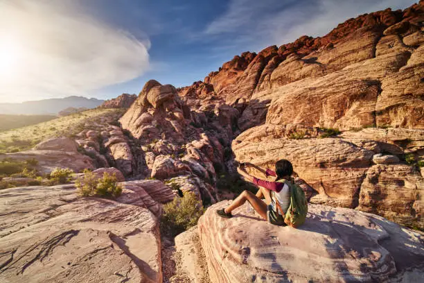 african american woman at red rock canyon taking selfie on ledge with lens flare