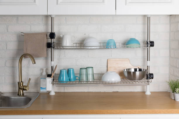 istock Clean dishes drying on metal dish rack on light background. Kitchen utensils and dishware on wooden shelf. Kitchen interior background.Text space. 1042614534