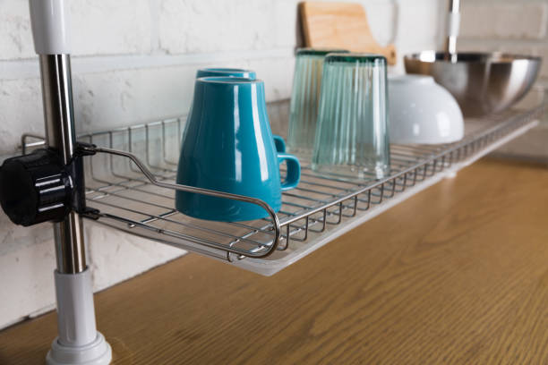 istock Clean dishes drying on metal dish rack on light background. Kitchen utensils and dishware on wooden shelf. Kitchen interior background.Text space. 1042614612