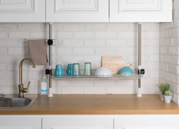 istock Clean dishes drying on metal dish rack on light background. Kitchen utensils and dishware on wooden shelf. Kitchen interior background.Text space. 1042614676