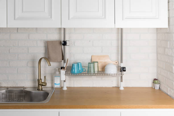 istock Clean dishes drying on metal dish rack on light background. Kitchen utensils and dishware on wooden shelf. Kitchen interior background.Text space. 1042614850