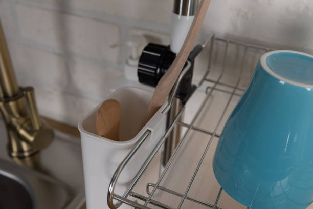 istock Clean dishes drying on metal dish rack on light background. Kitchen utensils and dishware on wooden shelf. Kitchen interior background.Text space. 1042614866