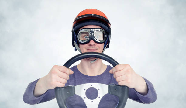 istock Man in red helmet and goggles with steering wheel. car driver concept 1042617672