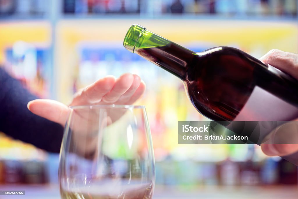 Woman rejecting more alcohol from wine bottle in bar Womans hand rejecting more alcohol from wine bottle in bar Alcohol - Drink Stock Photo