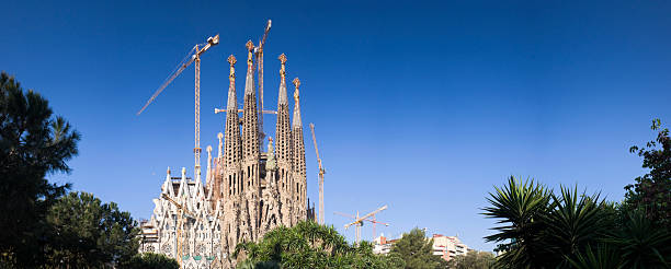 Barcelona, Spain - June 14, 2022:  Tourist crowd admires the architectural detail of the gothic Art Nouveau church spires of the Sagrada Familia basilica in the Eixample district of Barcelona Catalonia Spain