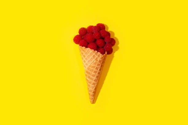 istock Raspberries in an ice cream cone on a table on a yellow background. 1042621352