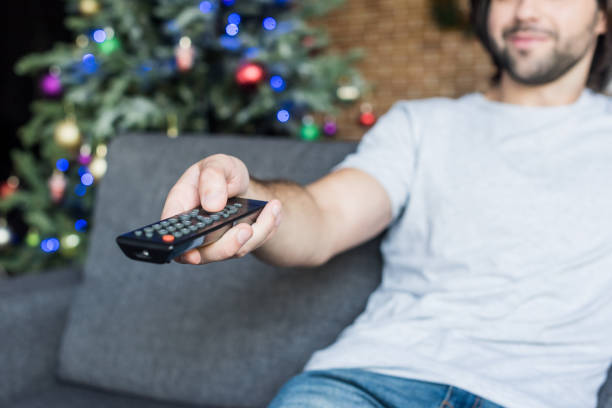 istock close-up view of man using remote controller while sitting on couch at christmas time 1042645864