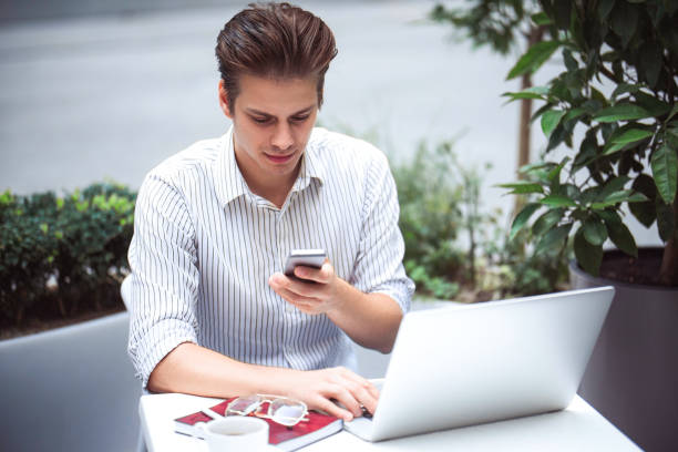istock Attractive businessman using a laptop and smiling while working in cafe. 1042647968