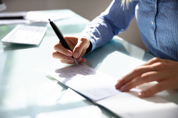 Businesswoman Signing Cheque Close-up Of A Businesswoman's Hand Signing Cheque signing cheque stock pictures, royalty-free photos & images