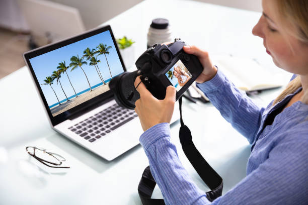 Female Editor Looking At Couple Photograph In DSLR Camera Female Editor Looking At Couple Photograph In DSLR Camera With Laptop On Desk editor photos stock pictures, royalty-free photos & images
