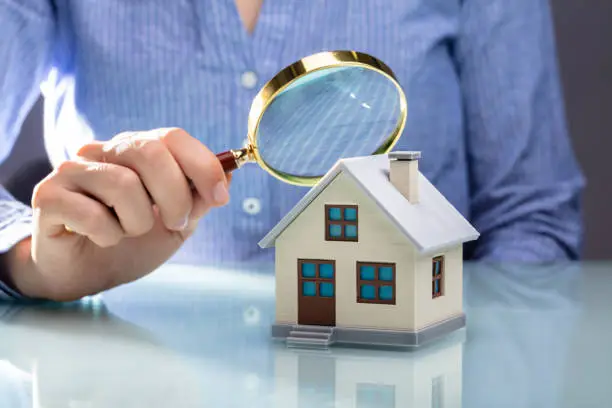 when a loved one passes away and leaves behind real estate, the executor or administrator often faces a complex task, businesswoman holding magnifying glass over house model