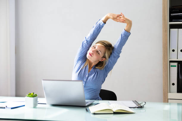 Businesswoman Stretching Her Arms Young Businesswoman Stretching Her Arms With Laptop On Desk office competition stock pictures, royalty-free photos & images