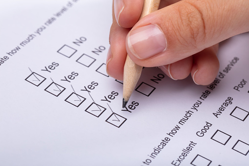 Close-up Of A Woman's Hand Ticking Yes Choice On Review Form