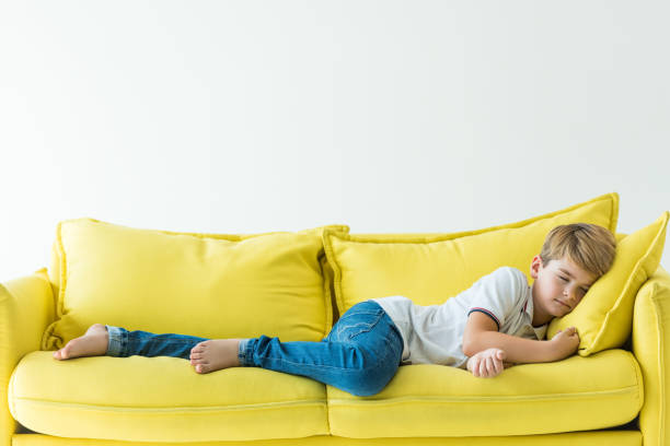 istock adorable boy sleeping on yellow sofa isolated on white 1042650852