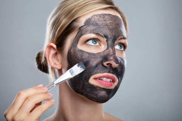 istock Woman Applying Activated Charcoal Face Mask With Brush 1042651590
