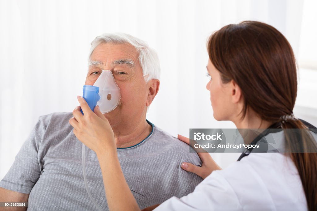 Docteur Holding masque à oxygène sur le visage de l’homme - Photo de Bronchopneumopathie chronique obstructive libre de droits