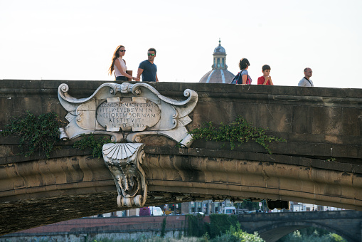 Florence, Italy – August 28, 2018: People walking over the bridge of the Santa Trinita. Some are taking photos. It takes them over the river Arno