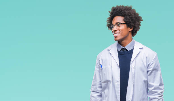 médecin américain afro homme de scientifique sur fond isolé vous cherchez loin à côté avec le sourire sur le visage, expression naturelle. riant confiant. - scientist male young adult doctor photos et images de collection