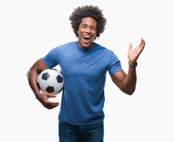 afro americano homem segurando uma bola de futebol isolada expressão muito feliz e animado, vencedor de fundo comemorando a vitória gritando com um grande sorriso e levantou as mãos - football human hand holding american football - fotografias e filmes do acervo