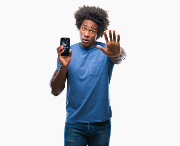 istock Afro american man holding broken smartphone over isolated background with open hand doing stop sign with serious and confident expression, defense gesture 1042723864