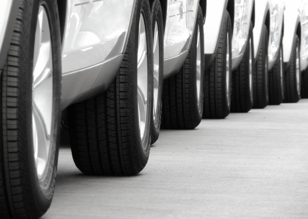 Line of the wheels of same vehicles staying on the road Wheels of new white cars laid out in lines on the asphalt convoy stock pictures, royalty-free photos & images