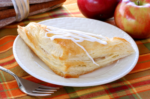 Slices of freshly baked homemade pie with apples, walnuts and cinnamon. On baking paper and a wooden table