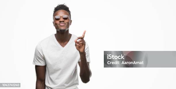 젊은 아프리카계 미국인 남자 착용 선글라스 놀된 생각 또는 행복 한 얼굴 넘버 원 가리키는 손가락 질문 남자에 대한 스톡 사진 및 기타 이미지