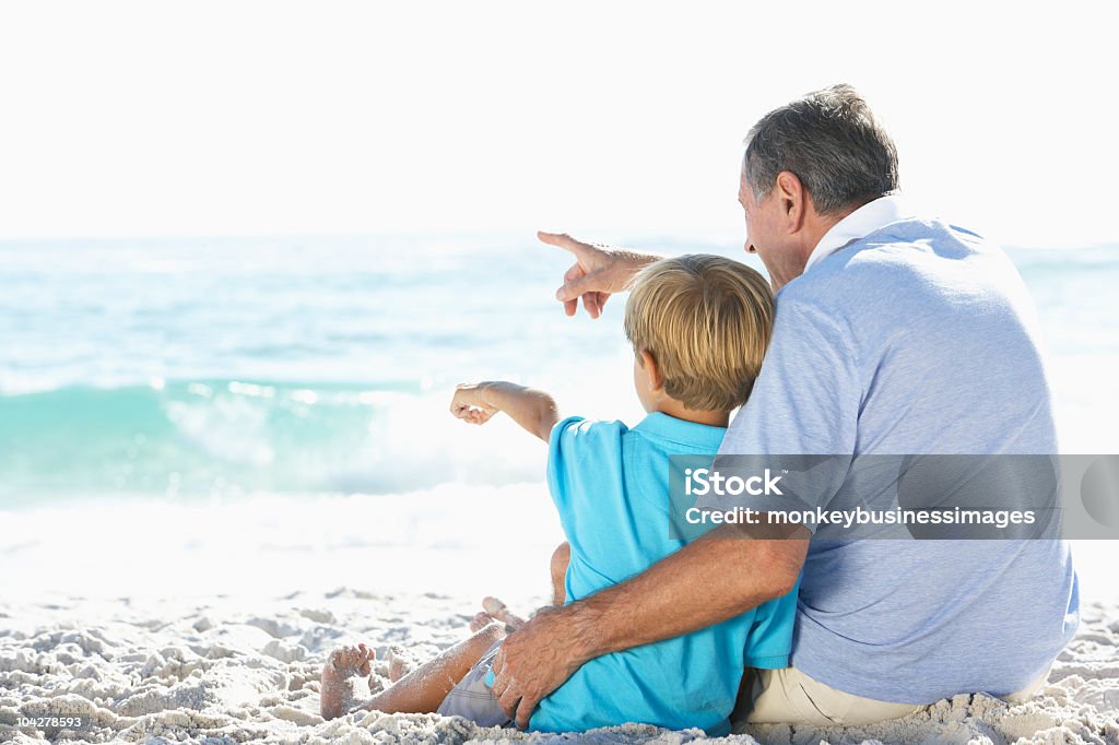 Grandfather And Grandson Sitting On Beach  Beach Stock Photo