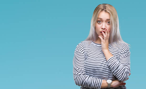 Young blonde woman over isolated background looking stressed and nervous with hands on mouth biting nails. Anxiety problem. Young blonde woman over isolated background looking stressed and nervous with hands on mouth biting nails. Anxiety problem. Phobia stock pictures, royalty-free photos & images