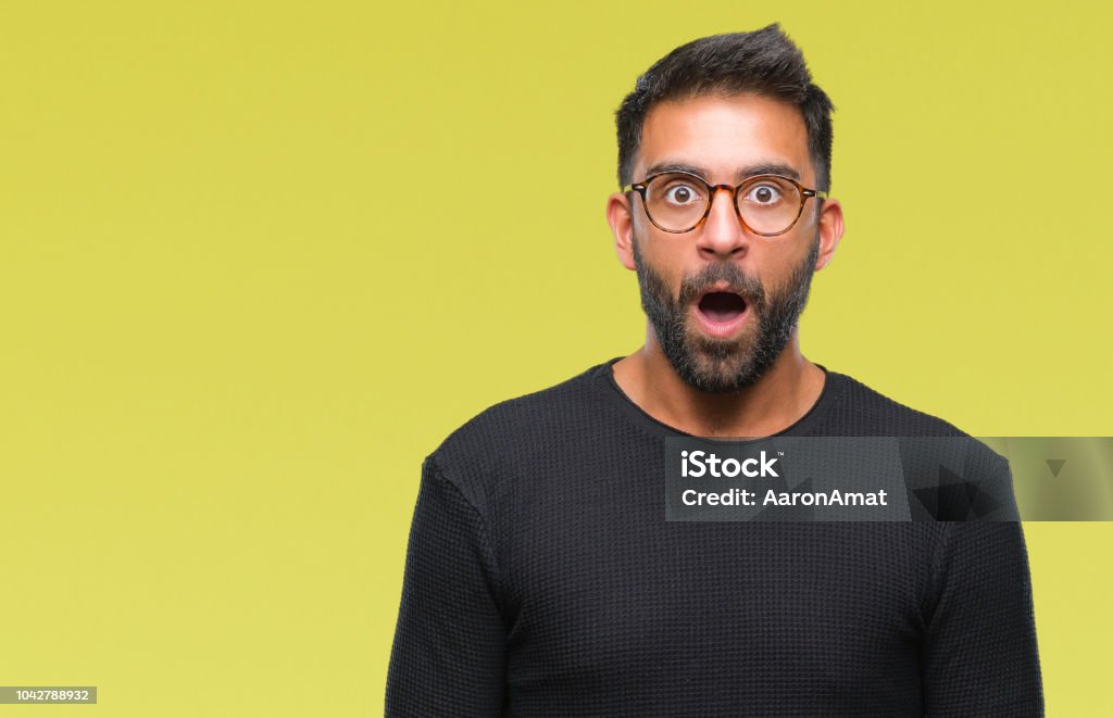 Adult hispanic man wearing glasses over isolated background afraid and shocked with surprise expression, fear and excited face. Surprise Stock Photo