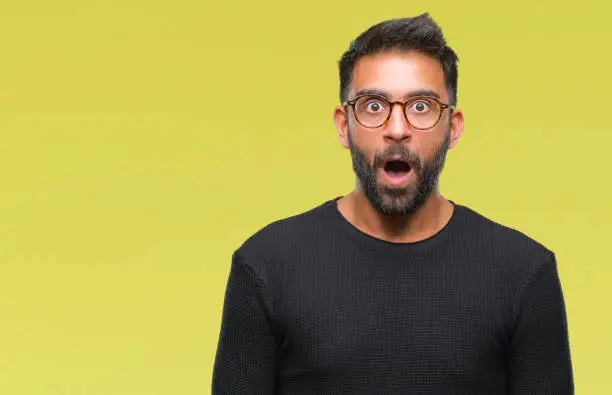 Photo of Adult hispanic man wearing glasses over isolated background afraid and shocked with surprise expression, fear and excited face.