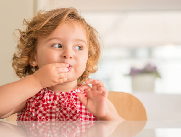 красивый маленький ребенок, милая маленькая девочка дома - child eating стоковые фото и изображения