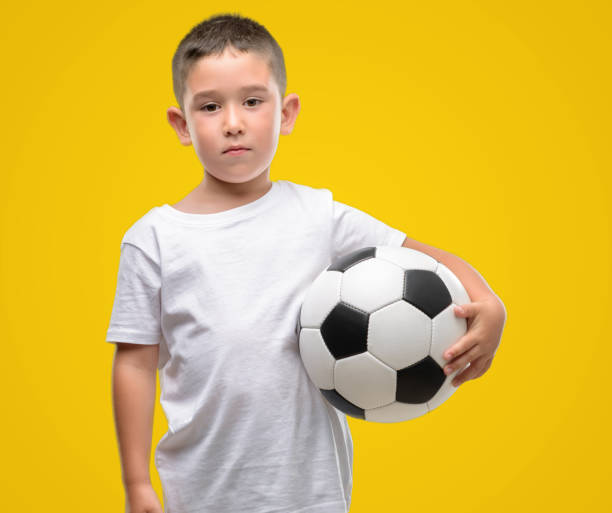 istock Dark haired little child playing with soccer ball with a confident expression on smart face thinking serious 1042792904