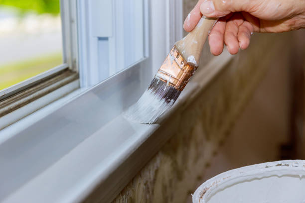Close up of man hand carefully painting the edge of an house window Close up of a man hand carefully painting the edge of an house window moulding trim photos stock pictures, royalty-free photos & images