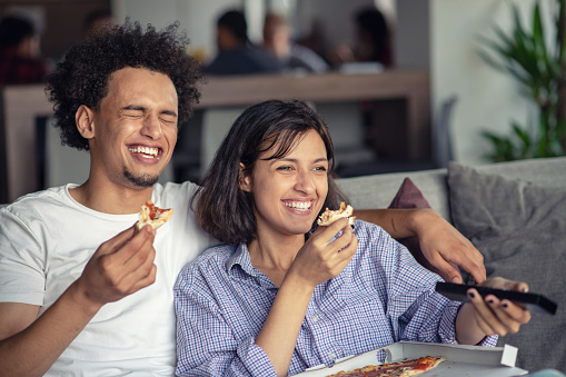 Young Couple with pizza and TV remote.