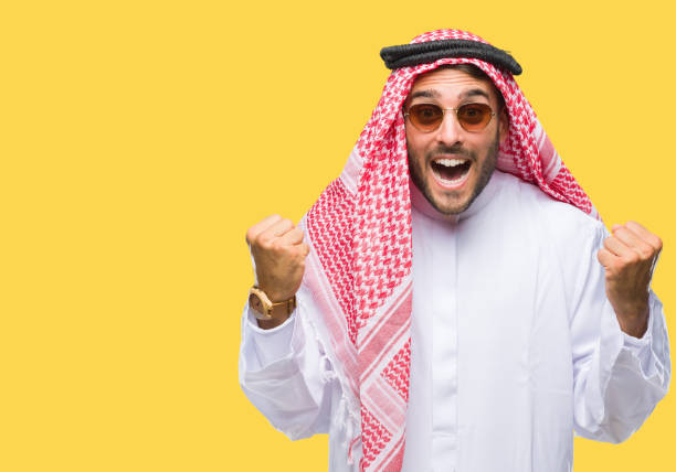 Young handsome man wearing keffiyeh over isolated background celebrating surprised and amazed for success with arms raised and open eyes. Winner concept. Young handsome man wearing keffiyeh over isolated background celebrating surprised and amazed for success with arms raised and open eyes. Winner concept. kaffiyeh stock pictures, royalty-free photos & images