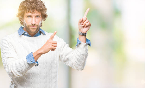 istock Handsome hispanic man model wearing winter sweater over isolated background smiling and looking at the camera pointing with two hands and fingers to the side. 1042827288