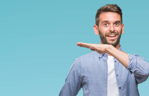 istock Young handsome man wearing white t-shirt over isolated background gesturing with hands showing big and large size sign, measure symbol. Smiling looking at the camera. Measuring concept. 1042830248