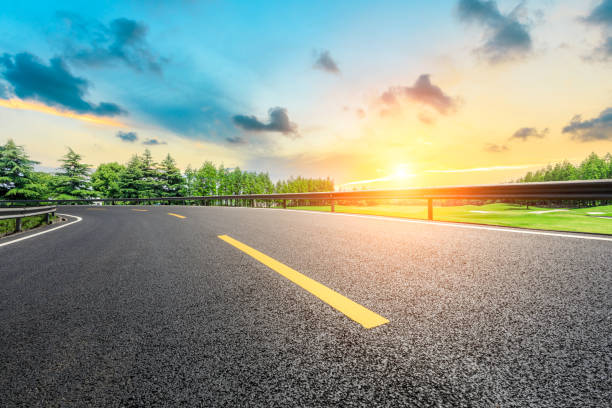 istock Asphalt road and green forest with colorful clouds at sunset 1042846708