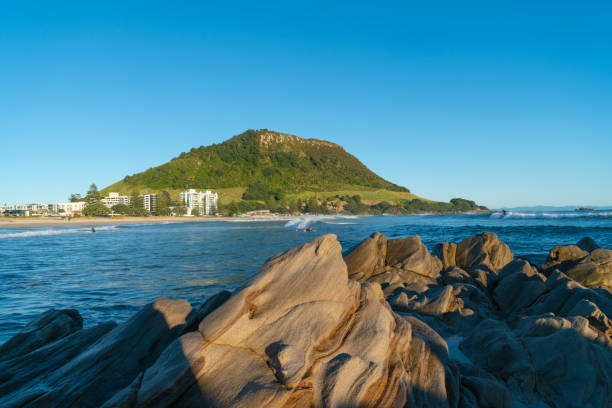 Landmark Mount Maunganui Landmark Mount Maunganui as sun rises and casts shadows over foreground rock mount maunganui stock pictures, royalty-free photos & images