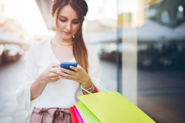 istock Young woman with shopping bags using smartphone. 1042857574