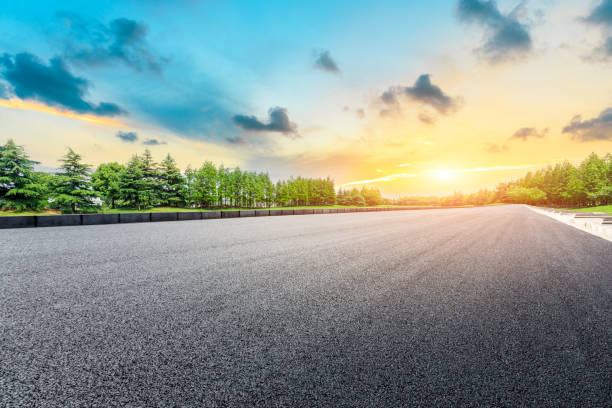 istock Asphalt road and green forest with colorful clouds at sunset 1042859896