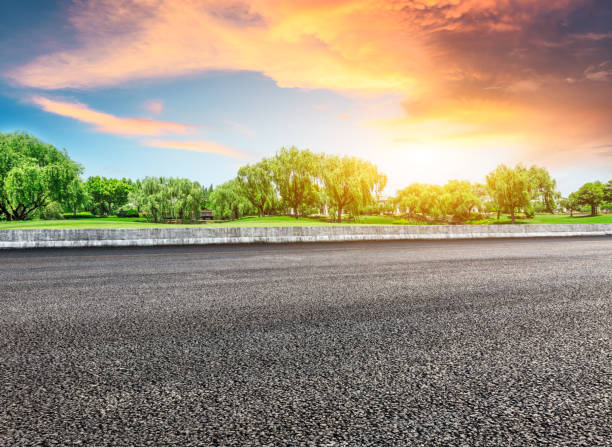 istock Asphalt road and green forest with colorful clouds at sunset 1042862654