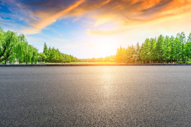 istock Asphalt road and green forest with colorful clouds at sunset 1042867738