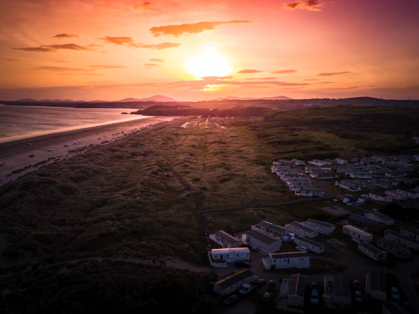 Sun Setting over the sea and Caravan and camping park, static home aerial view. stock photo